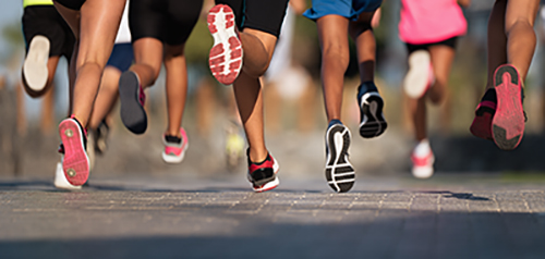 Image of a group of people running, showing only the bottom half of their bodies.