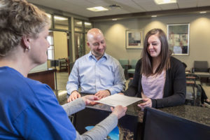 OSMS Surgery Center Receptionist providing patients with a payments or insurance form.